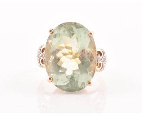 A 9ct yellow gold and green quartz cocktail ring, set with a large mixed oval-cut green stone, with diamond accents to should