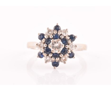 An 18ct white gold, diamond, and sapphire cluster ring, centred with a round brilliant-cut diamond of approximately 0.33 cara