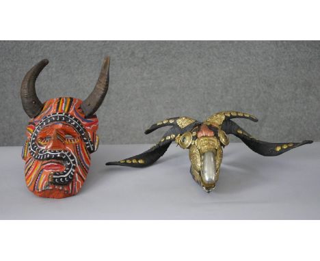 Two masks. One carved and painted with sheep's horns and the other a sheep's skull with gilt metal and copper embossed embell