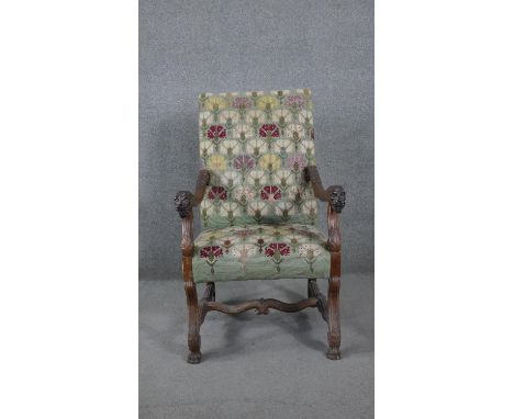 A 19th century Continental walnut armchair in stylised floral tapestry upholstery and lion carved masks on shaped stretchered