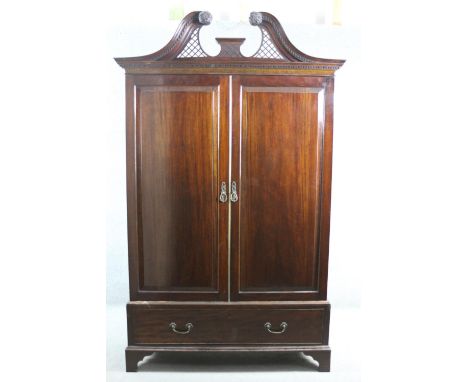 A 19th century mahogany wardrobe with pierced arched swan neck pediment above fielded panel doors enclosing fabric lined hang