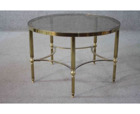 A mid century vintage smoked glass and brass lamp table on shaped stretchered supports. H.40 Diam.62cm. 