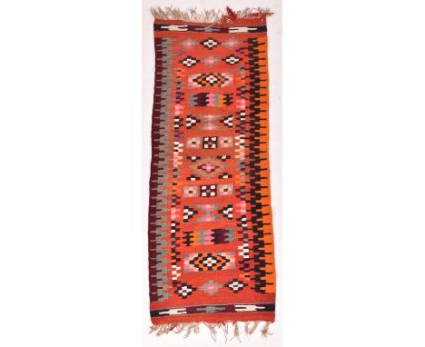 A 20th century Kilim Turkish floor carpet / rug runner. The rug featuring red ground with polychrome geometric patterning, en