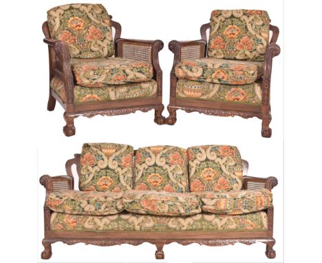 An early 20th century three piece mahogany and double caned bergere suite. The suite comprising a three seater sofa and two a