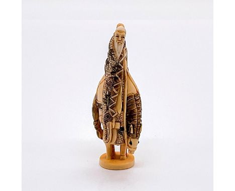 A netsuke figure of Kosekiko the Yellow Stone Elder on a horse. His robe adorn with carved leaves and red Asian vector circle