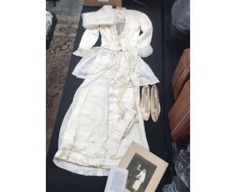 An Edwardian wedding dress and silk stockings (circa 1912) made up of cream crepe de chine. the bodice has a 'V' neck edged i