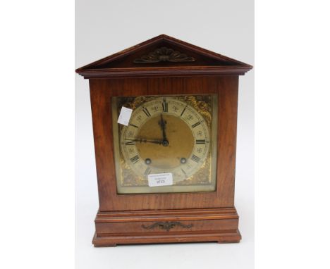 A late Victorian walnut eight day mantle clock, silvered chapter ring with Roman numerals, gilt spandrels, striking on a gong