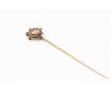 A yellow metal stick pin with tortoise finial and tiny diamond eyes