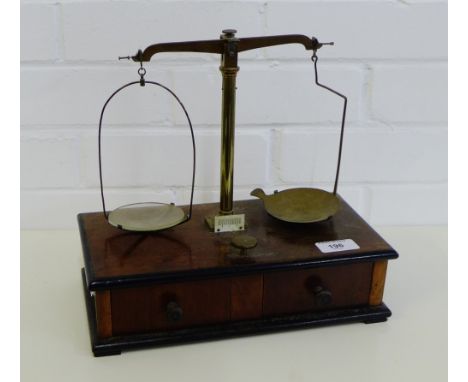 A set of brass balance scales on a mahogany base with two drawers