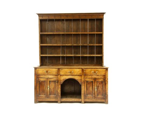 A George III oak dresser, the three shelf plate rack over three drawers, and a pair of cupboards flanking an open 'dog kennel