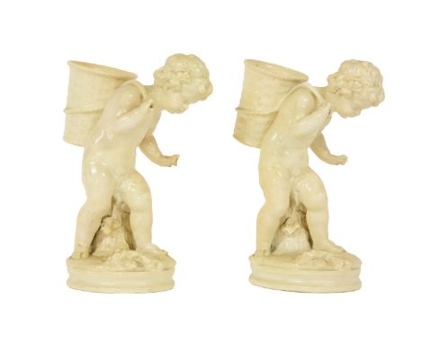 A pair of Royal Worcester blanc de chine figures, of putti carrying a basket, 21cm high