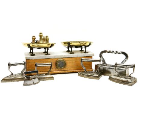 A set of marble topped scales, together with an assortment of various weights, and six flat irons