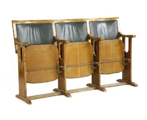 A vintage set of three cinema seats, the oak frames with hinged seats and bowed pad backs, numbered one, two and three. 157 x