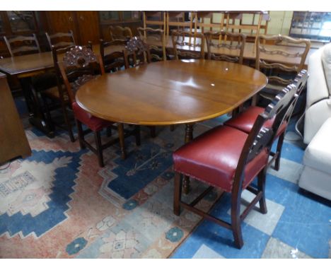 An Extending Mahogany Oval Topped Dining Table and Four Carved Oak Framed Ladder Back Chairs 