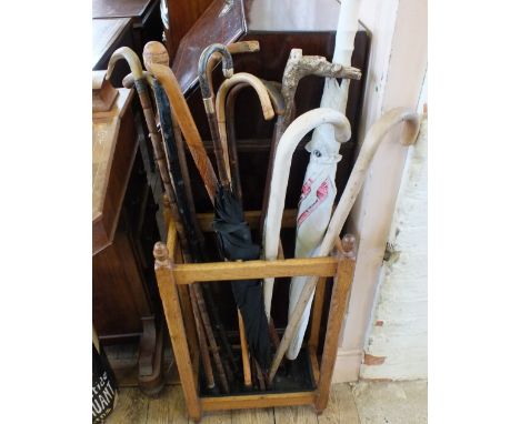 An Oak stick stand containing a horn handled stick, other walking sticks and a 9ct Gold banded umbrella