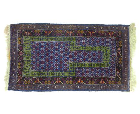 A Persian prayer rug with blue ground, green stylised arch on the purple and cream decorated field, black and dark blue borde