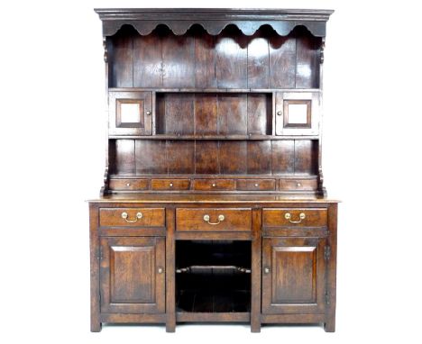 A modern reproduction Georgian style oak Welsh dresser, circa 2000, shaped cornice over a closed back two shelf plate rack wi