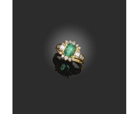 An emerald and diamond ring, claw-set with a step-cut emerald, within a border of brilliant-cut diamonds, the shoulders set w
