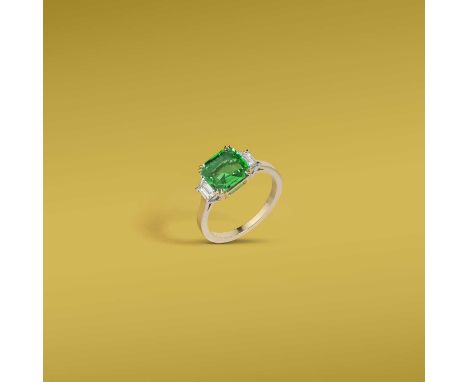 A fine emerald and diamond ring, claw-set with a cushion-shaped emerald weighing 1.73 carats, between shoulders set with trap