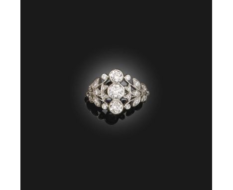 A diamond-set platinum ring, with three graduated circular-cut diamonds millegrain-set within pierced and graduated foliate s