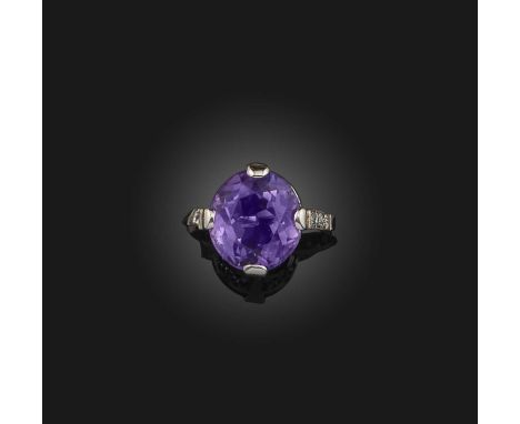 An amethyst and diamond ring, the oval amethyst set within diamond shoulders in platinum and palladium, size M
