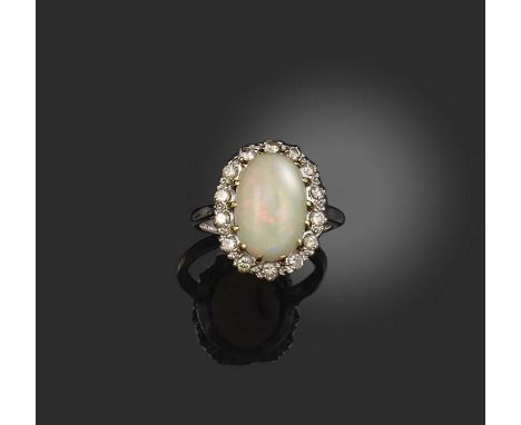 An opal and diamond cluster ring, set with a solid white opal within a surround of diamonds in platinum, size P