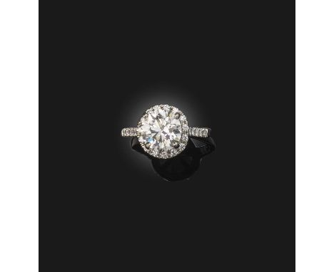 A diamond ring, of cluster design, claw-set with a brilliant-cut diamond weighing 3.02 carats, to a border and shoulders set 