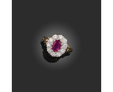 A ruby and diamond cluster ring, set with a central oval-shaped ruby within a surround of round brilliant-cut diamonds in pla