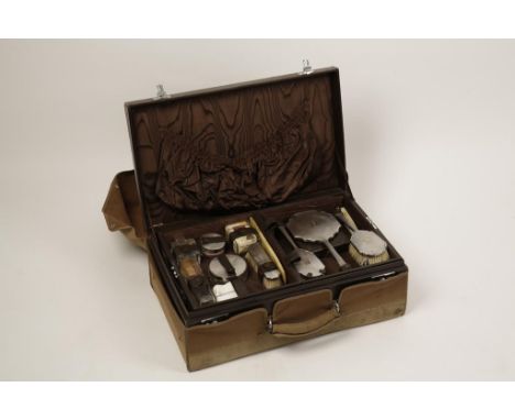 A TRAVELLING VANITY CASE containing a silver backed engine-turned dressing table set and various glass mounted pots and bottl
