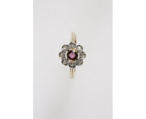 A RUBY AND DIAMOND FLOWERHEAD RING, collet-set in yellow gold to the centre with a round-cut ruby and surrounded by a shaped 