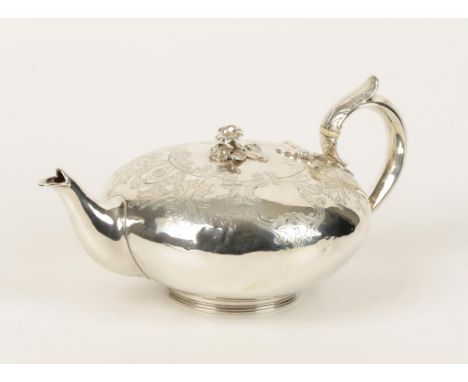 A VICTORIAN TEAPOT of compressed circular form with leaf-capped scroll handle and flowerhead finial, the body chased with fol