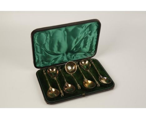 A VICTORIAN SILVER GILT SET OF SIX SERVING SPOONS, in a case, with a matching sifter ladle, the finials with figural terminal