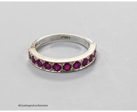   A modern 18ct white gold and eleven stone ruby set half eternity ring, size L, gross 3.7 grams.