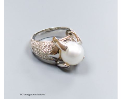   A modern white metal (stamped 750) and claw set cultured pearl dress ring, with pave diamond set shoulders, size R, gross 1