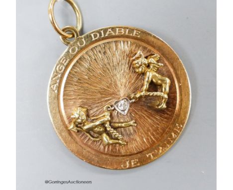   A 14k yellow metal and diamond set circular pendant, depicting articulated figures of an angel and devil in a tug-o-war and