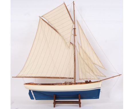 A vintage well built wooden model yacht. In two tone blue and cream hull colour scheme, with fully rigged sails. On stand. 85