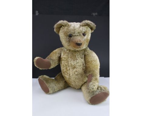 Mid 20th C teddy bear with glass eyes, soft filled, showing some wear and nose repair but gd overall, 25" approx height, with