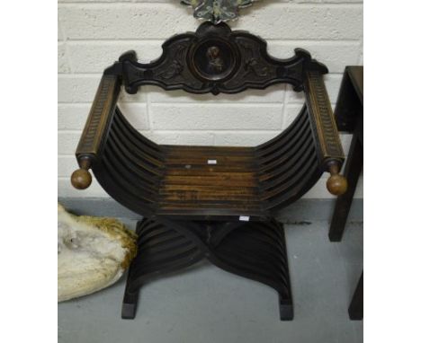 A SEVENTEENTH CENTURY STYLE CARVED WALNUT X-FRAMED CHAIR. The shaped back with a centre profile portrait on relief, probably 