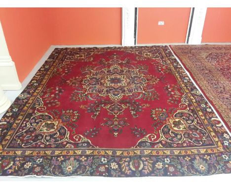 A VERY ATTRACTIVE TABRIZ CARPET, with floral deep-burgundy field and centre medallion,within multicolour spandrels and a wide