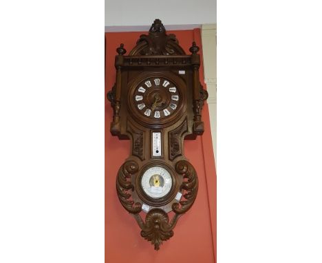 AN UNUSUAL LATE NINETEENTH AND EARLY TWENTIETH CENTURY CARVED WALNUT WALL CLOCK/ BAROMETER. The arched top with a cartouche c