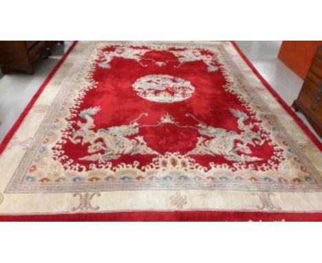 A CHINESE WOOL CARPET, with centre medallion, with four dragon spandrels inside an ivory, fawn, red and blue border. 12ft4 (3