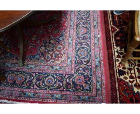 A PERSIAN MASHAD CARPET, with traditional centre medallion. On burgundy ground with all-over floral pattern. Conforming spand