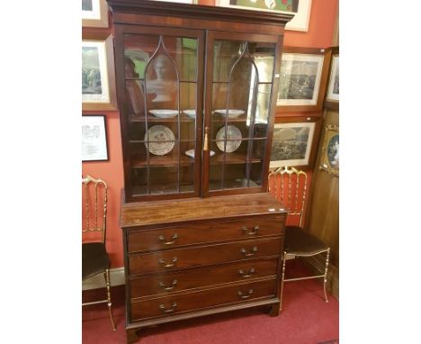 A GEORGE IV PERIOD MAHOGANY BOOKCASE. Moulded cornice above two gothic glazed doors, each with eight panels, enclosing three 