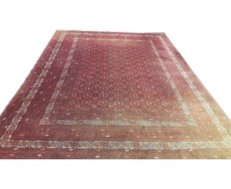 A LARGE DARK-RED GROUND BOKHARA CARPET, with rows of small medallions, inside a wide four-band red border. 11ft4 (345cm)l x 8