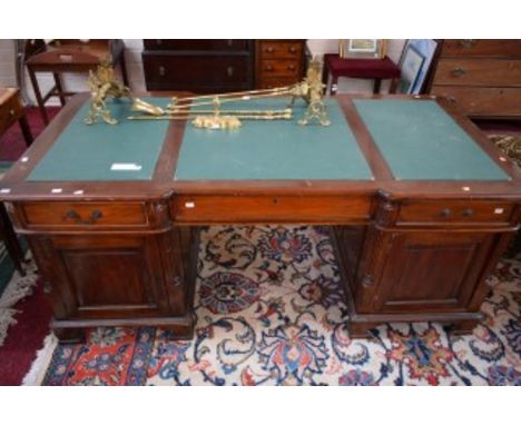 A GEORGIAN STYLE MAHOGANY PEDESTAL WRITING DESK, of inverted breakfront outline. The top with three inset writing panels, abo