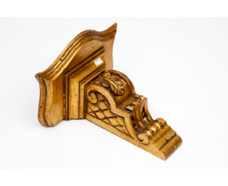 A CARVED GILT-WOOD WALL BRACKET. O.R.M.. With serpentine-shaped shelf, on corbel style bracket, 13" (33cm) high x 13" (33cm) 