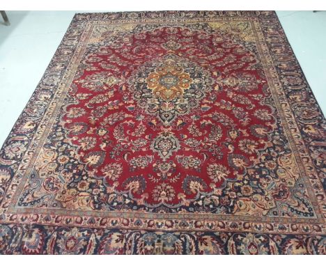 A FINE PERSIAN MASHAD CARPET. Dark burgundy ground with floral medallion and all-over floral pattern, in conforming spandrels