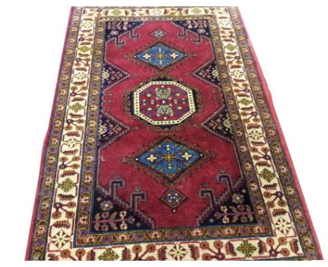 AN ORIENTAL RUG, with large octagonal red centre medallion and two light-blue triangular medallions, on a burgundy ground, in
