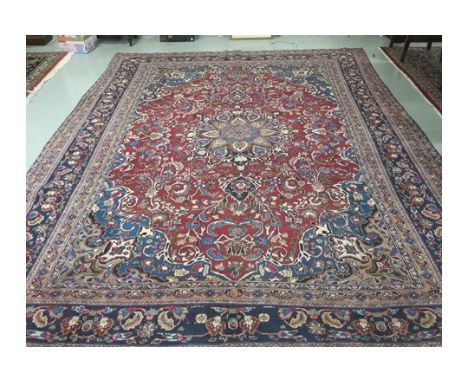 A PERSIAN MASHAD CARPET, with centre medallion, on an all over floral burgundy ground, within seven borders. 12ft 8" (386cm) 