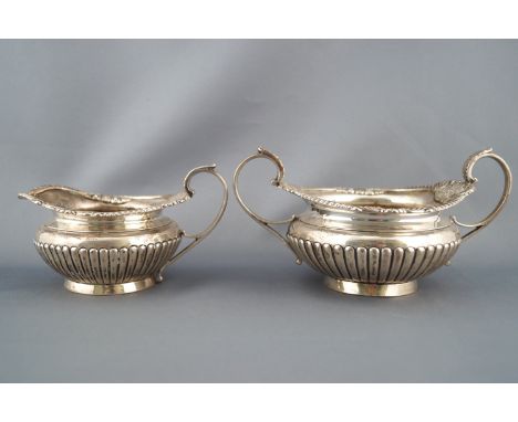 A silver Regency style three piece tea service, of rounded form, the tea pot with a flattened fluted lid in a gadrooned surro